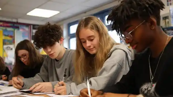 A group of students sitting together in class, focused on writing and studying — representing the real lessons teachers learn from their students beyond the IELTS test.